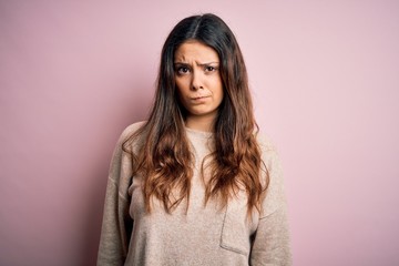 Fototapeta premium Young beautiful brunette woman wearing casual sweater standing over pink background skeptic and nervous, frowning upset because of problem. Negative person.