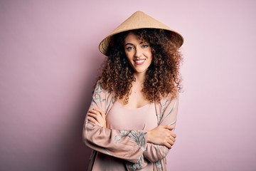 Young beautiful woman with curly hair and piercing wearing traditional asian conical hat happy face smiling with crossed arms looking at the camera. Positive person.