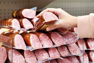 Smoked sausage in hands at store