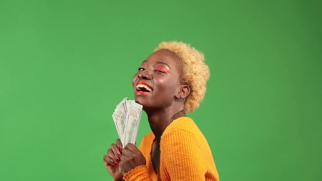 Beautiful American rich woman spending money on useless thing, isolated green background. studio shot.