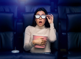 Asian woman in 3D glasses watching horror movie in cinema
