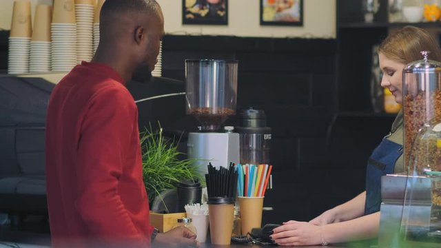 cafe bar girl employee performs order payment taking African client credit card and using terminal close view slow motion
