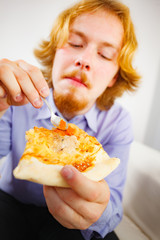 Man eating pizza adding tomato sauce