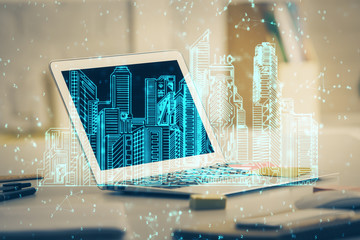 Desktop computer background in office and big town buildings hologram drawing. Double exposure. Smart city concept.