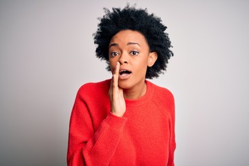 Young beautiful African American afro woman with curly hair wearing red casual sweater hand on mouth telling secret rumor, whispering malicious talk conversation