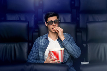 Young man in 3D glasses watching interesting movie in cinema