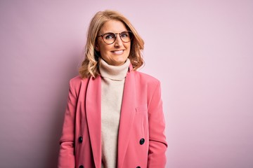 Middle age beautiful blonde business woman wearing elegant pink jacket and glasses with a happy and...