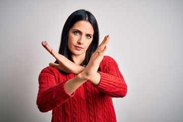 Young brunette woman with blue eyes wearing casual sweater over isolated white background Rejection expression crossing arms doing negative sign, angry face