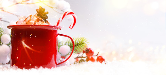Enamel cup of hot cocoa with marshmallows and candy canes
