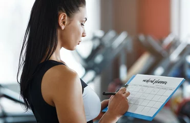 Foto op Plexiglas Personal trainer with clipboard making workout plan in gym © Prostock-studio