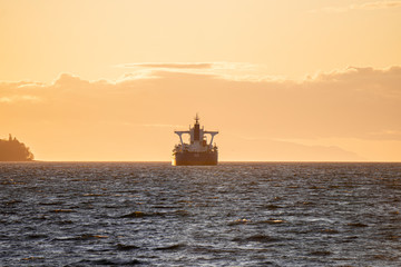 sunset on beach with rocks in the front and large  cargo boat near island  on water pacific ocean Pacific north west PNW Vancouver Canada boats waiting vertical photo 