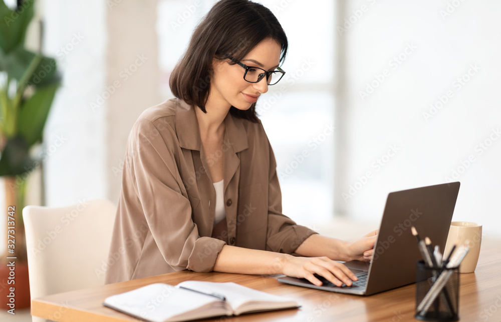 Wall mural beautiful girl working on her laptop at contemporary office