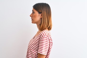 Beautiful redhead woman wearing casual striped red t-shirt over isolated background looking to...