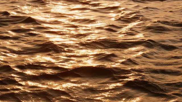 Abstract shot of moving waves surface in golden sea waters