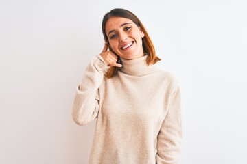 Beautiful redhead woman wearing winter turtleneck sweater over isolated background smiling doing phone gesture with hand and fingers like talking on the telephone. Communicating concepts.