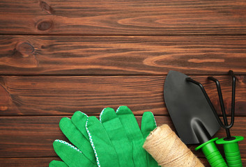 Gardening tools on brown wooden background, top view