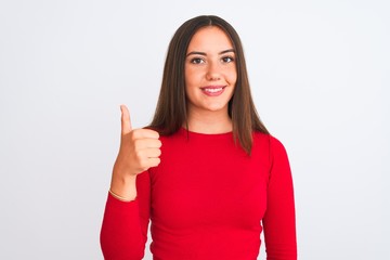 Young beautiful girl wearing red casual t-shirt standing over isolated white background doing happy thumbs up gesture with hand. Approving expression looking at the camera showing success.