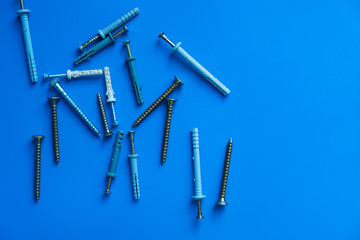 Many different nails screws nuts bolts on blue background of the copy space. Construction and repair concept