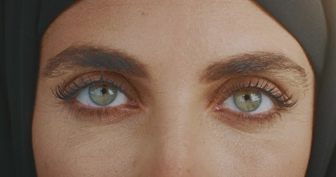 Extreme close up of a woman's green eyes opening gazing into the camera