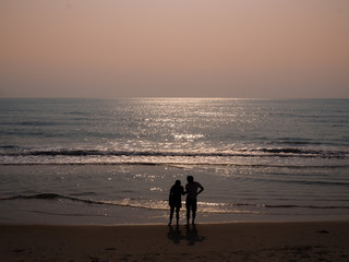  SIlhouette of a couple holding hands at the beach front with a beautiful morning sunlight background.the beach front with a beautiful morning sunlight background.