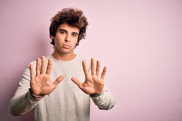 Young handsome man wearing casual t-shirt standing over isolated pink background Moving away hands...