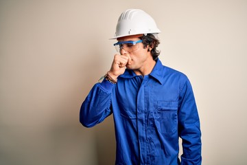 Young constructor man wearing uniform and security helmet over isolated white background feeling unwell and coughing as symptom for cold or bronchitis. Health care concept.