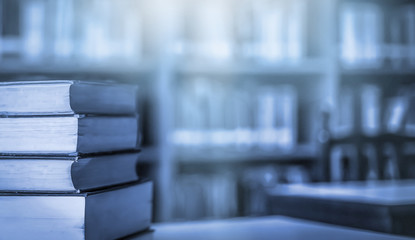 Obraz premium Stack of books in the library and blur bookshelf background 