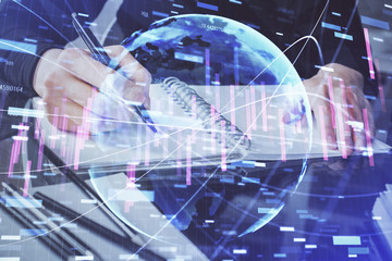 Forex chart hologram on hand taking notes background. Concept of analysis. Multi exposure