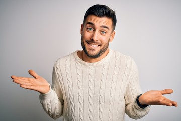 Young handsome man wearing casual sweater standing over isolated white background clueless and...