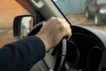 Man's hand holding the steering wheel of a car close-up