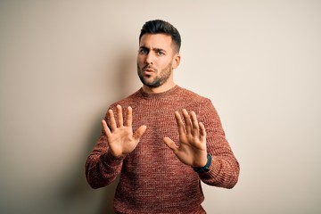 Young handsome man wearing casual sweater standing over isolated white background Moving away hands...