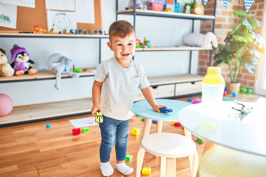 Adorable toddler smiling happy. Standing playing around lots of toys at kindergarten