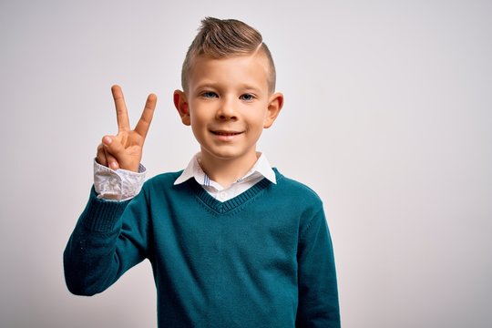 Young little caucasian kid with blue eyes standing wearing elegant clothes over isolated background smiling with happy face winking at the camera doing victory sign. Number two.
