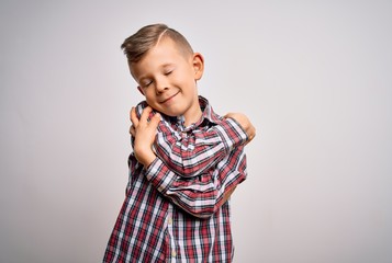 Young little caucasian kid with blue eyes wearing elegant shirt standing over isolated background Hugging oneself happy and positive, smiling confident. Self love and self care