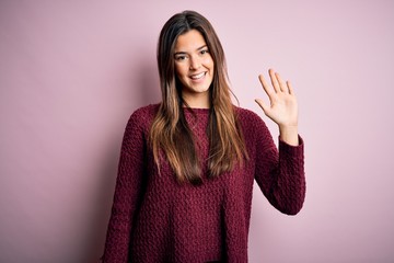 Young beautiful girl wearing casual sweater over isolated pink background showing and pointing up with fingers number five while smiling confident and happy.