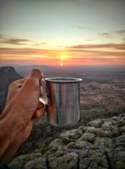 man drinking coffee on beach at sunset
