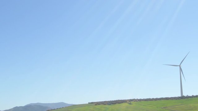 Wind turbine moving the blades and sunshine a sunny day with blue sky