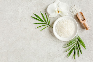 Fototapeta na wymiar Spa treatment concept. Natural/Organic spa cosmetics products, sea salt and tropic palm leaves on gray marble table from above. Spa background with a space for a text, flat lay, top view.