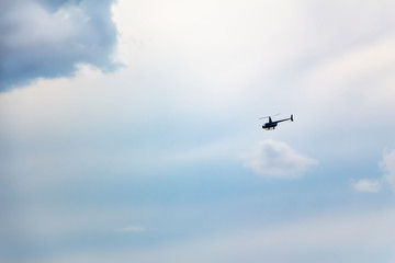 Fototapeta na wymiar helicopter in motion against a blue, cloudy sky