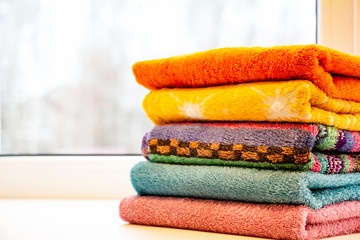 a stack of brightly colored towels on the windowsill