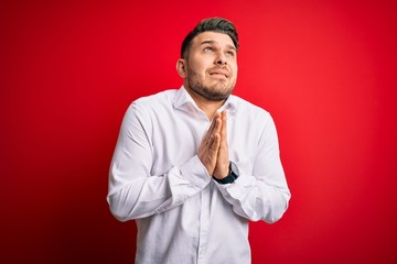 Young business man with blue eyes wearing elegant shirt standing over red isolated background...