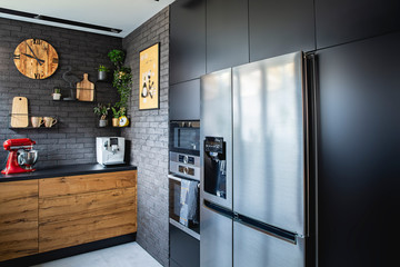 Big fridge in black kitchen with wooden furniture red kitchen robot and white coffee machine