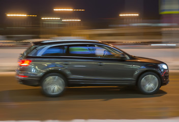 SUV moves through the night city in winter.