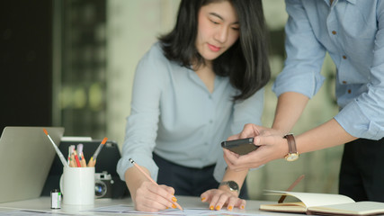 A team of professional designers are working with smartphone and laptops to design applications.