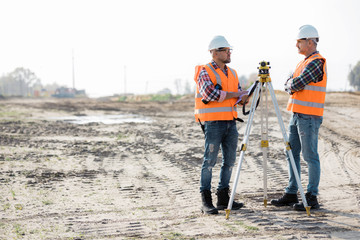 Two road construction workers using measuring device on the field