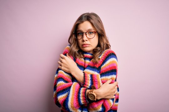 Young beautiful blonde girl wearing glasses and casual sweater over pink isolated background shaking and freezing for winter cold with sad and shock expression on face