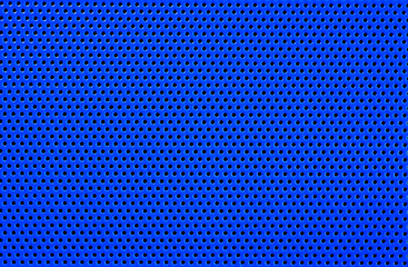 Macro of a blue plastic surface, with regular geometrically arranged round holes. Abstract blue background.
