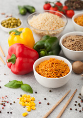 White bowl plates with boiled long grain basmati rice with vegetables and mushrooms on light table background with sticks and paprika pepper with corn,garlic and basil. Healthy vegan food.