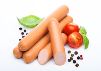Classic boiled meat pork sausages with pepper and basil and cherry tomatoes on white background. Macro