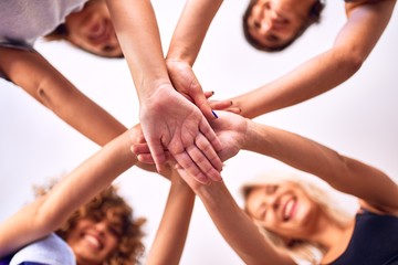 Young beautiful group of sportswomen standing shaking hands after class of yoga at gym